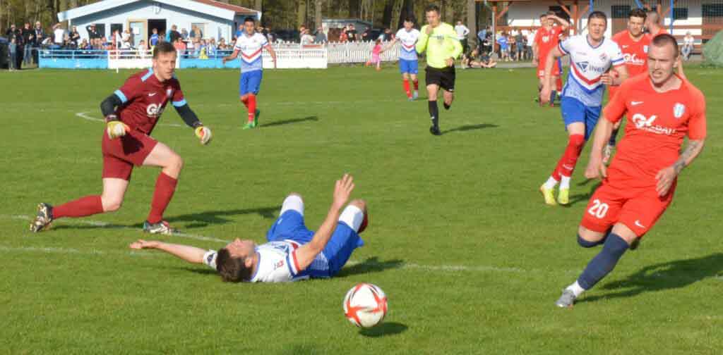 Kilkunastu mężczyzn na boisku, jeden leży