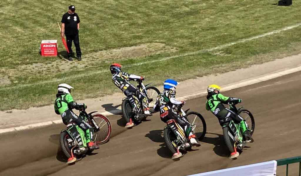 Cztery osoby na motocyklach i mężczyzna z czerwoną chorągiewką