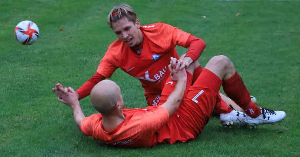 Dwaj mężczyźni leżą na boisku