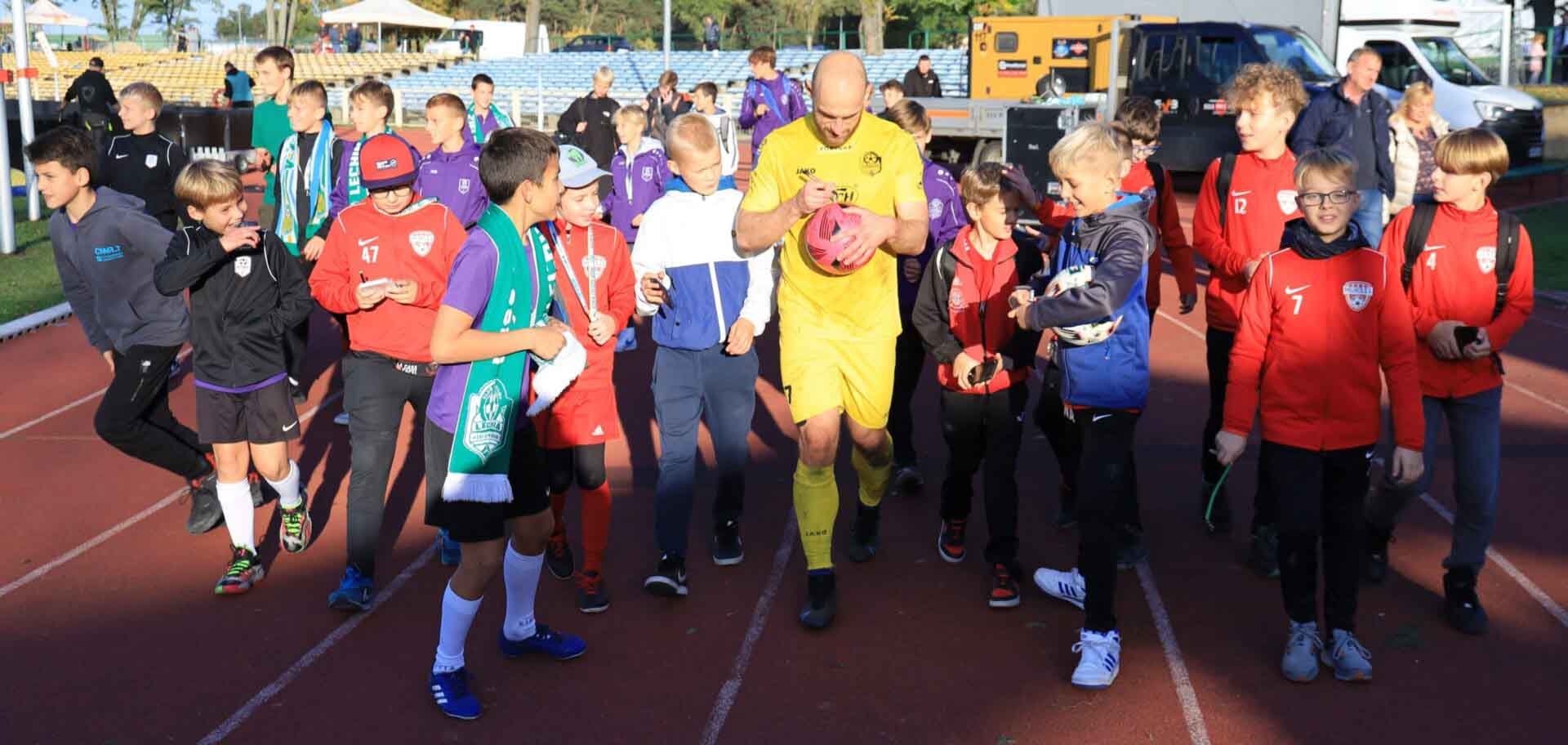 Mężczyzna w sportowym stroju otoczony grupą dzieci  Ruszyła sprzedaż biletów na mecz Lechia Zielona Góra  Radomiak Radom