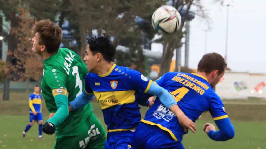 Trzej mężczyźni na boisku walczą o piłkę