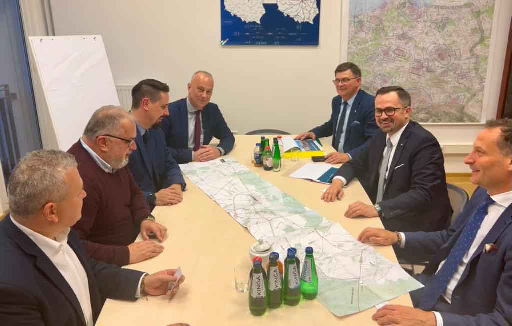 7 mężczyzn siedzących przy jednym stole.