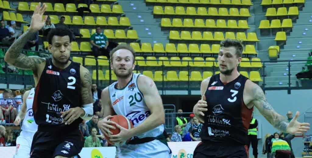 Trzej mężczyźni, jeden trzyma piłkę do koszykówki