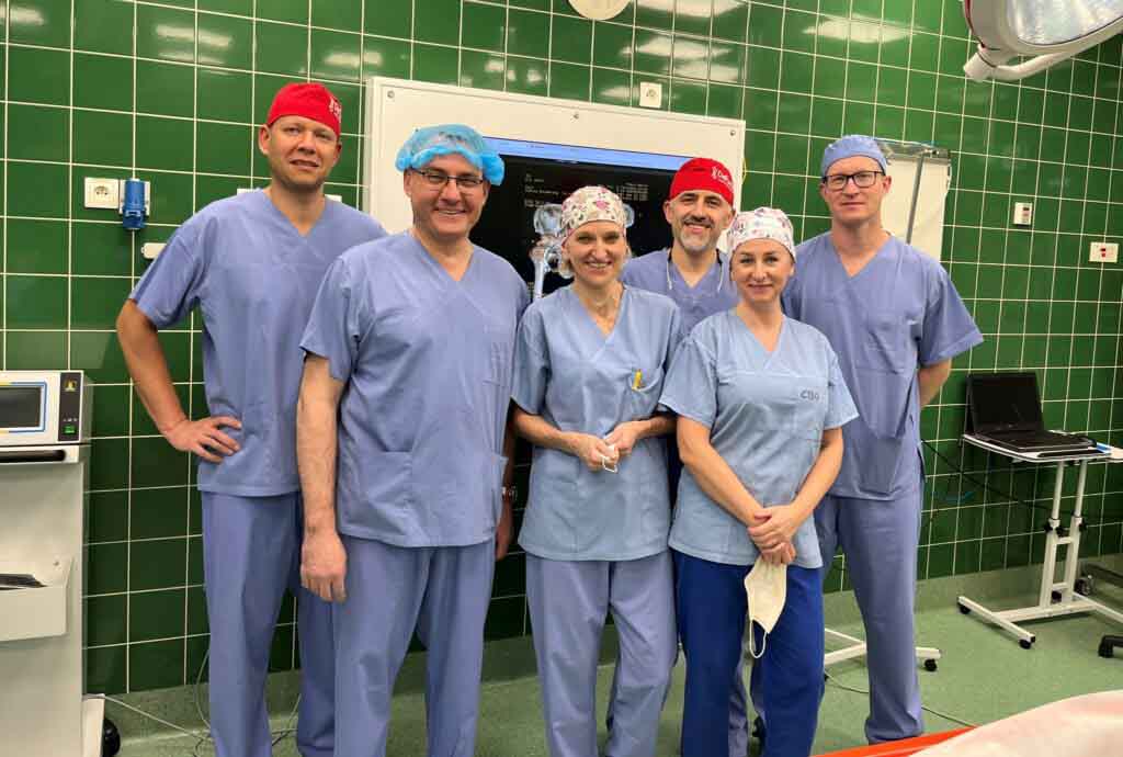 Sześć uśmiechniętych osób w medycznych fartuchach i czepkach