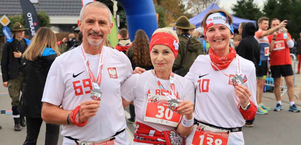 Troje uśmiechniętych ludzi - dwie kobiety i mężczyzna - z medalami