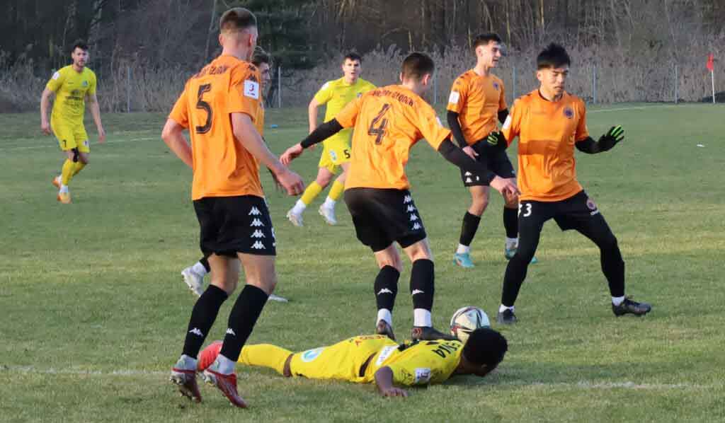 Ośmiu mężczyzn na boisku, jeden z nich leży