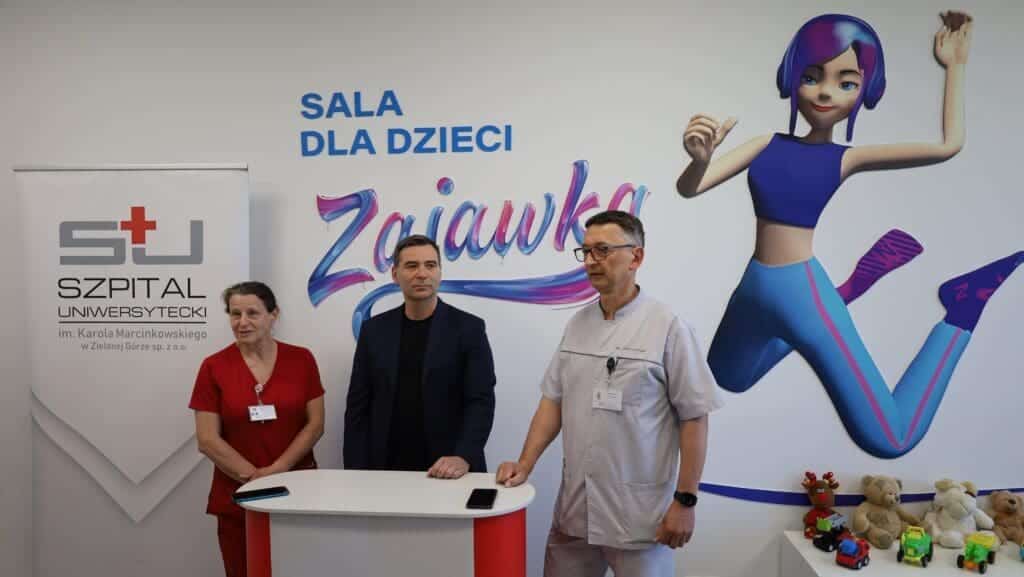 Kobieta i dwaj mężczyźni na tle napisu "Sala dla dzieci Zajawka"