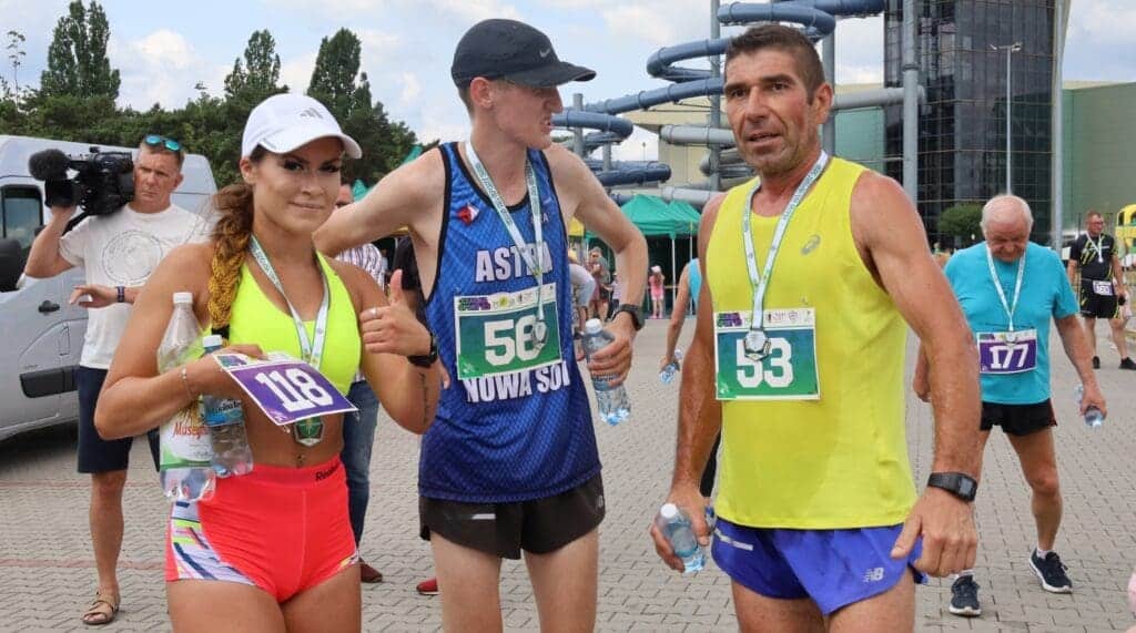 Kobieta i dwaj mężczyźni w sportowych strojach, z medalami