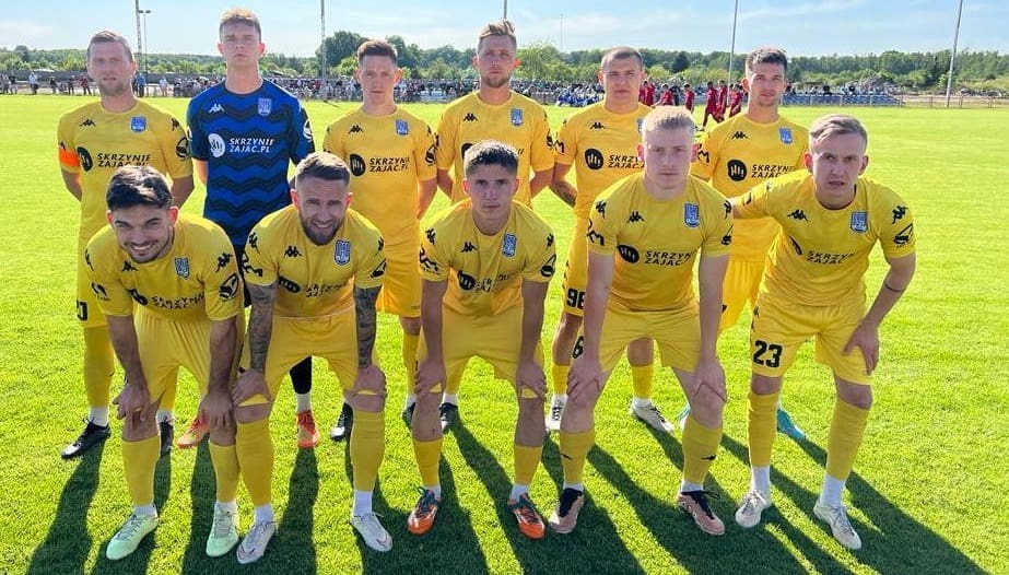 Jedenastu mężczyzn pozuje na tle boiska