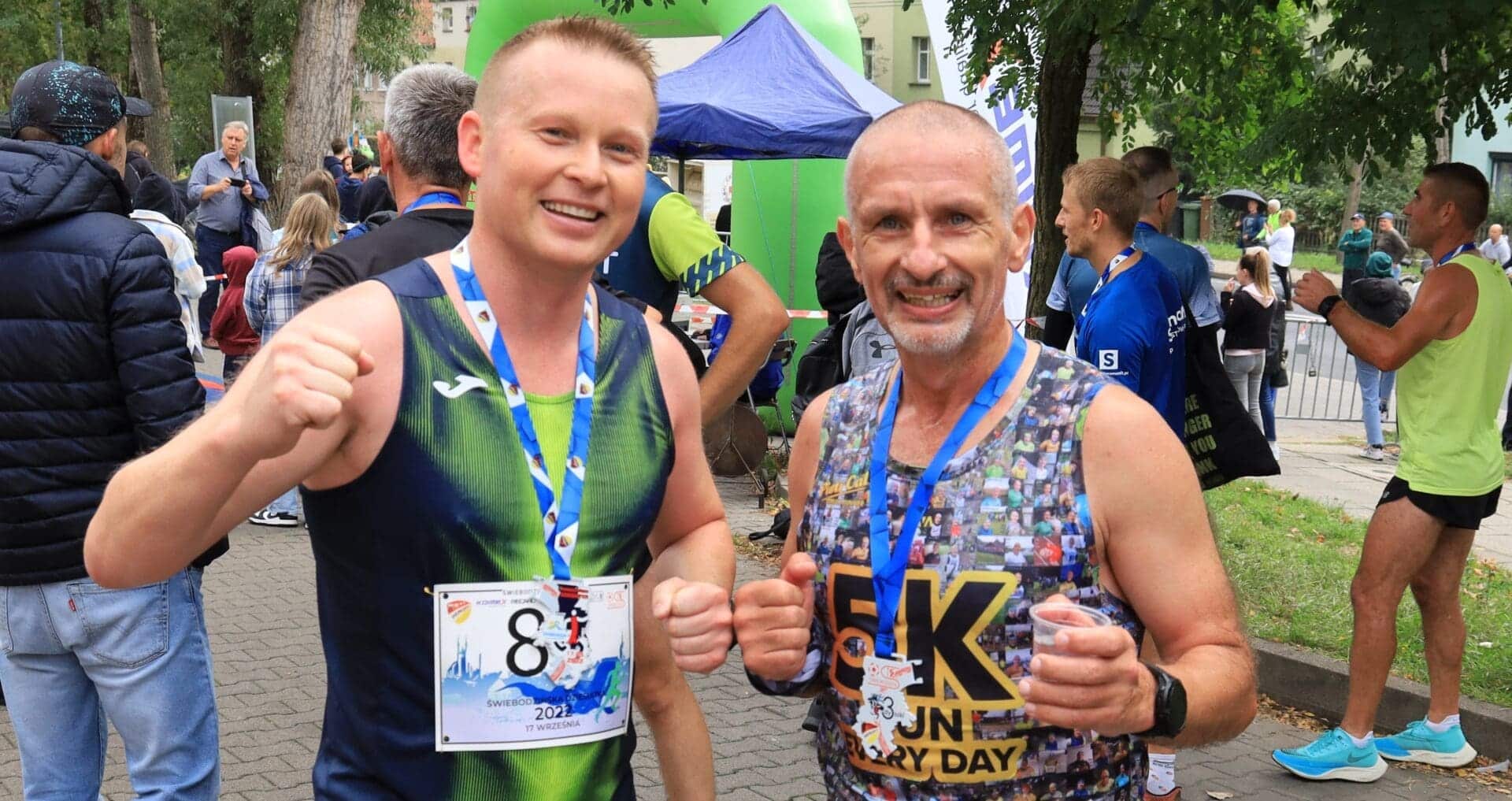 Dwaj uśmiechnięci mężczyźni w sportowych strojach  Zbliża się Świebodzińska Dziesiątka Nowa trasa Płasko a potem z górki