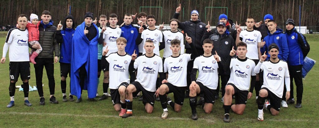 Grupa mężczyzn na boisku, wskazująca na niebo