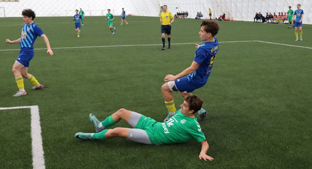 Dziewięciu młodych piłkarzy i sędzia na boisku