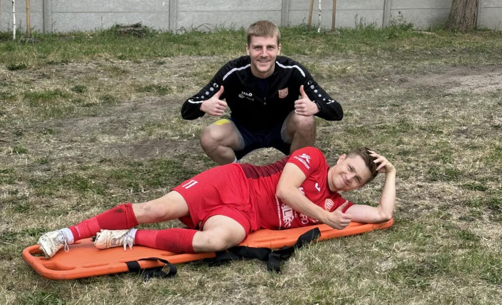 Dwaj mężczyźni w sportowych strojach, jeden na noszach