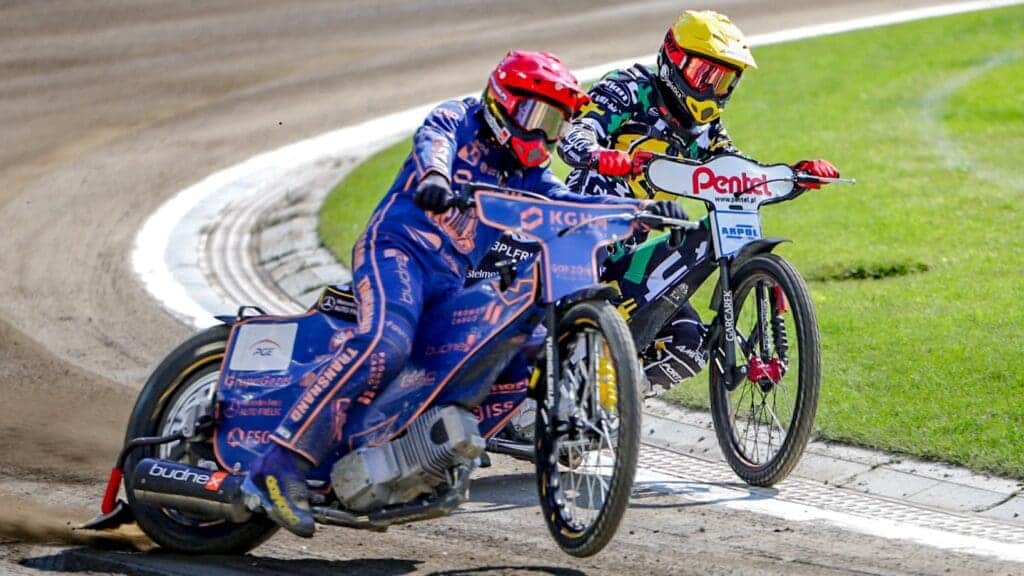 Dwie osoby ścigające się na żużlowych motocyklach