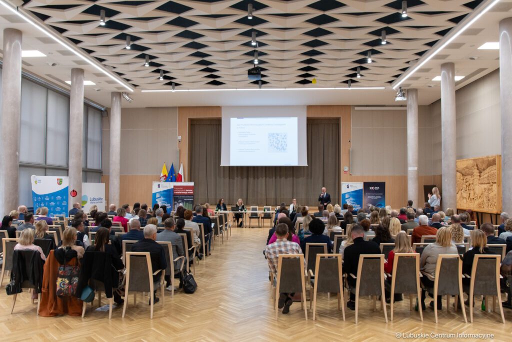 Ponad 100 osób siedzi na krzesłach w sali kolumowej UMWL na szkoleniu KPO dla samorządów