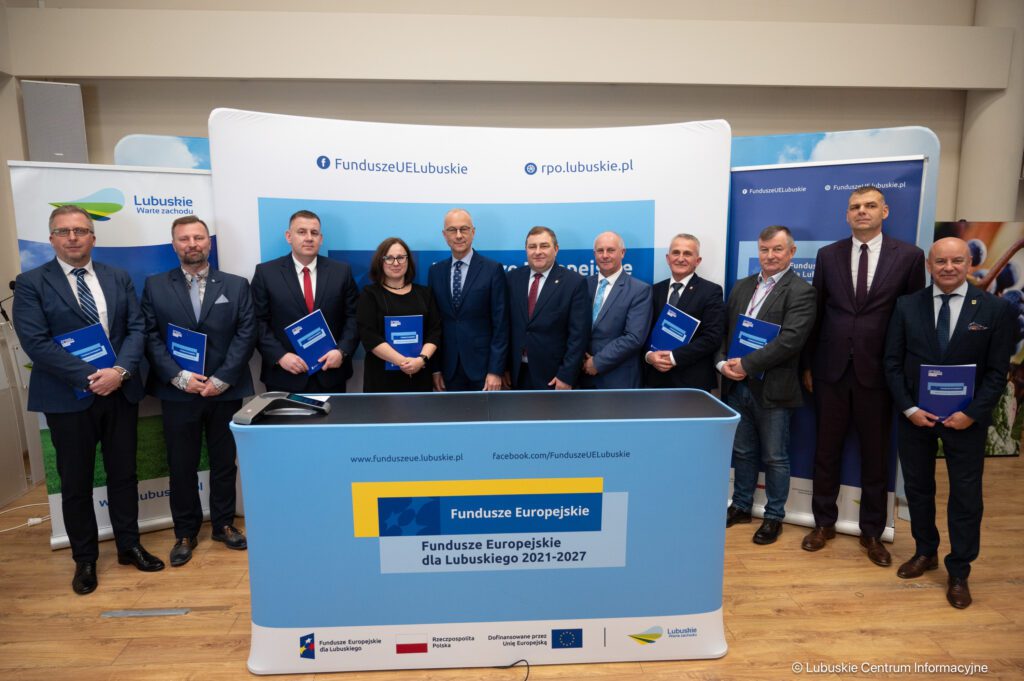 Przedstawiciele gmin, które podpisały umowy na CUS pozują na tle ścianki promocyjnej Funduszy Europejskich.