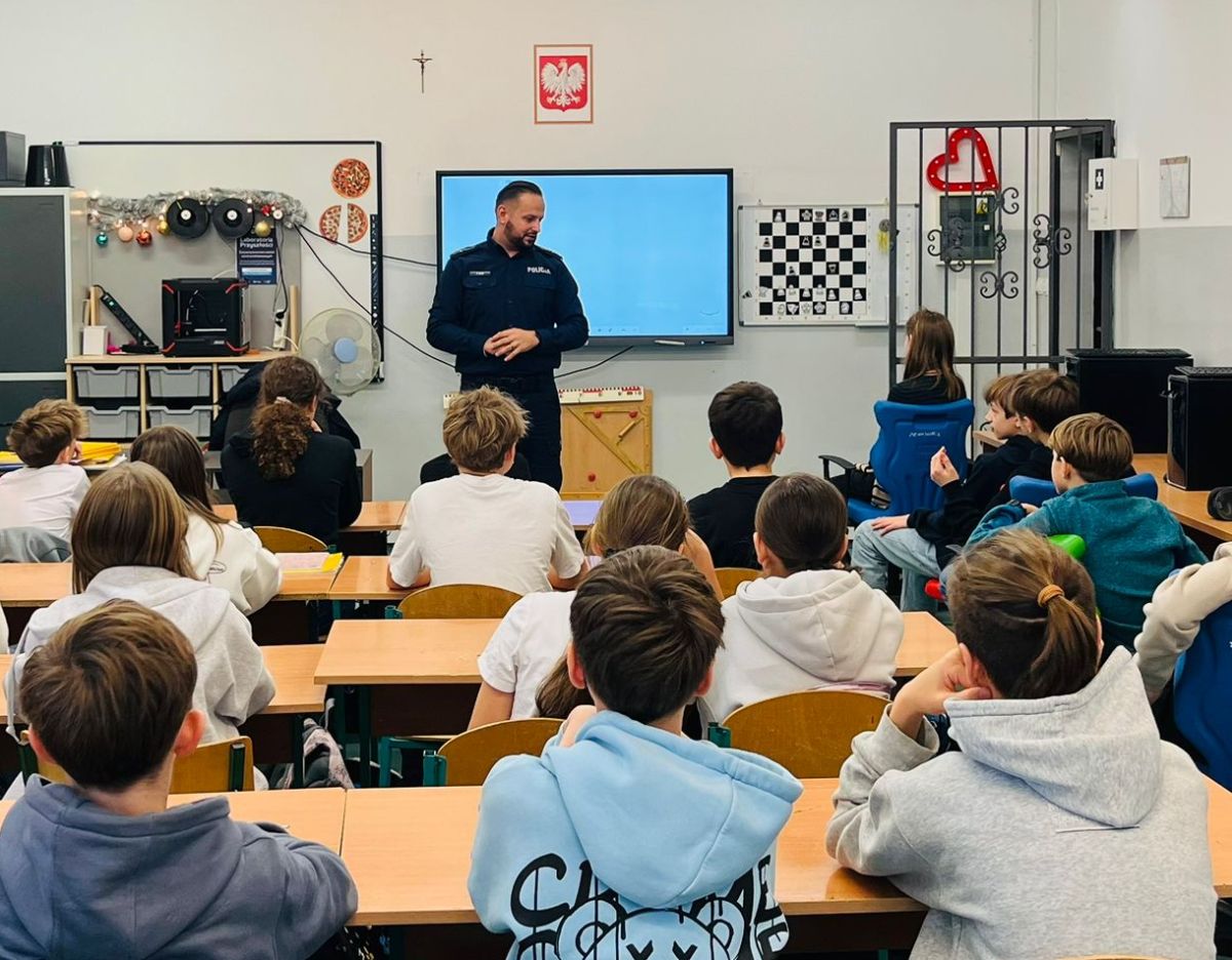Policjant podczas spotkania informacyjnego w klasie pełnej uczniów  Rusza akcja Bezpieczne ferie Policja min sprawdzi autokary jadące na kolonie