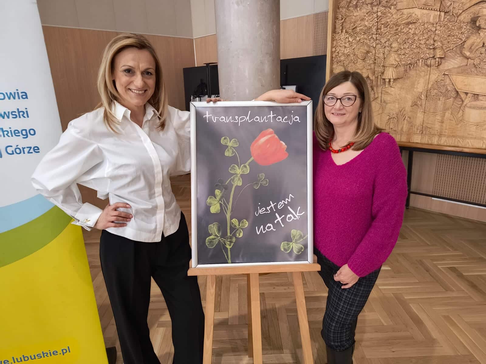 Dwie kobiety przy tablicy promującej transplantację  Żyje bo siostra oddała jej nerkę