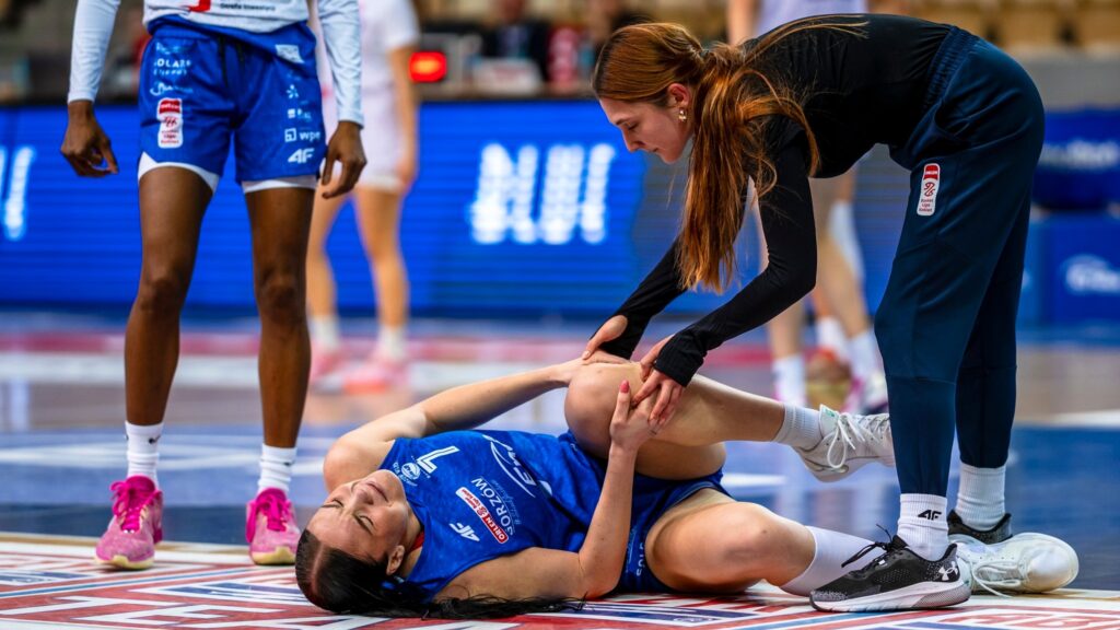 Kobieta w sportowym stroju leży na parkiecie