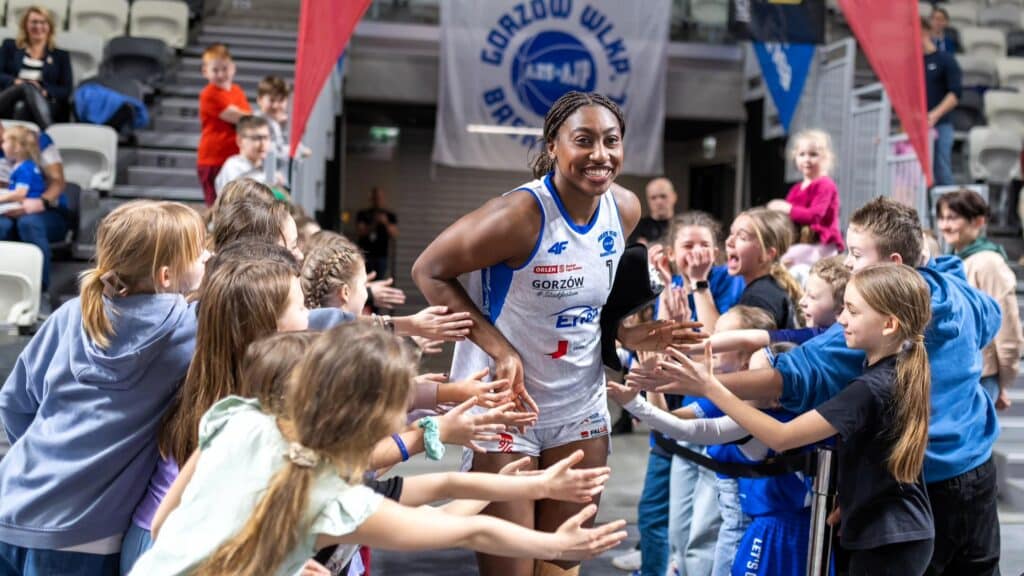 Uśmiechnięta kobieta w sportowym stroju wita się z dziećmi