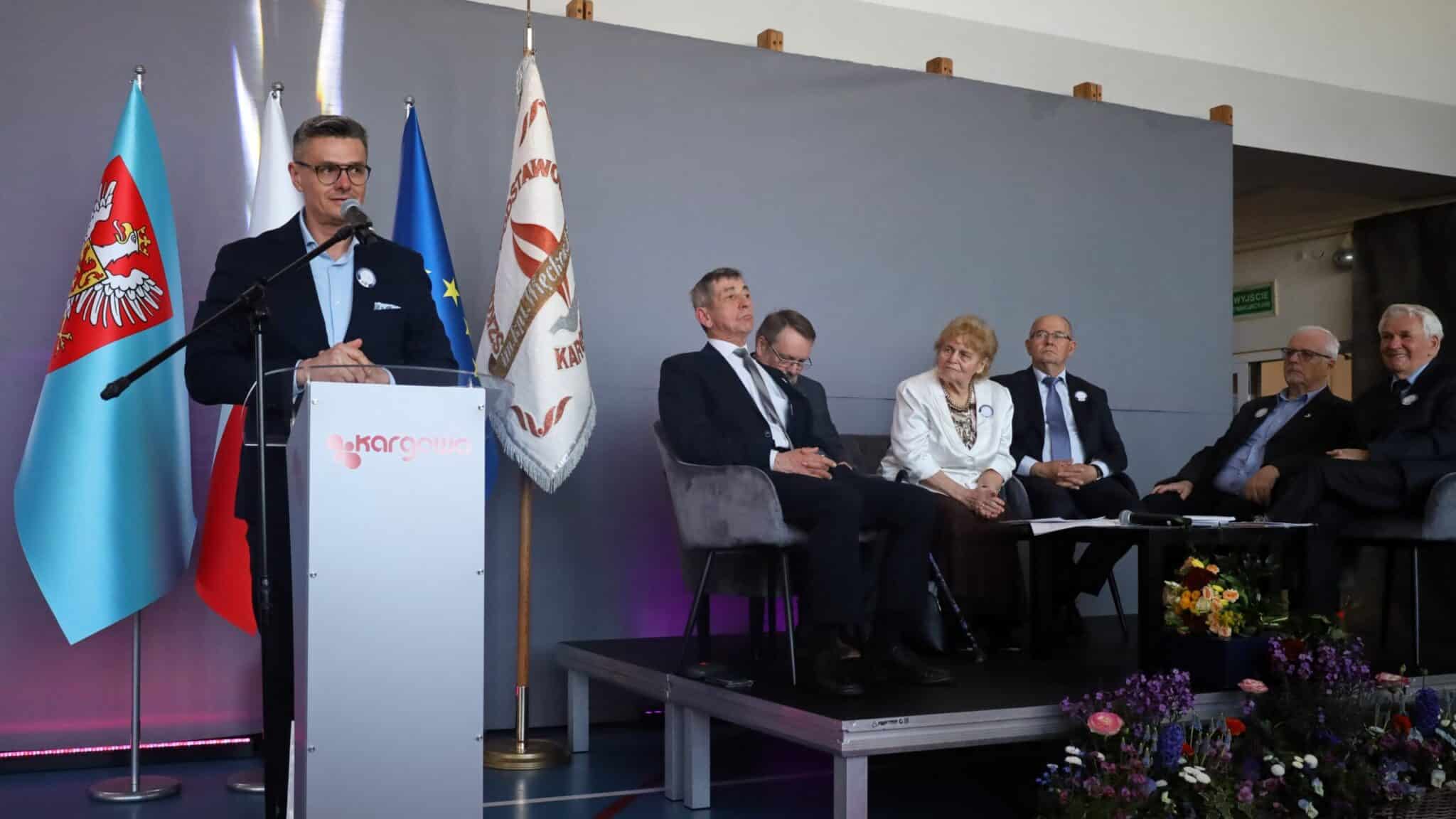 Mężczyzna przy mównicy i sześcioro osób w fotelach  80 lat minęło Zacny jubileusz Szkoły Podstawowej w Kargowej ZDJĘCIA