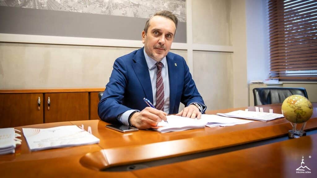 Mężczyzna w garniturze podpisujący dokumenty