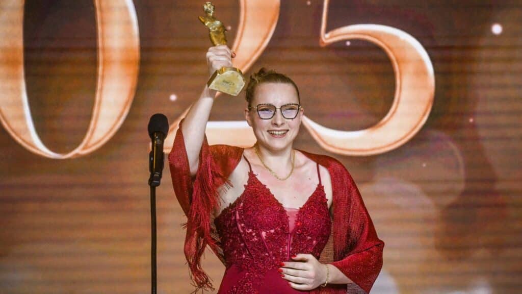 Usmiechnięta kobieta ze statuetką w ręku