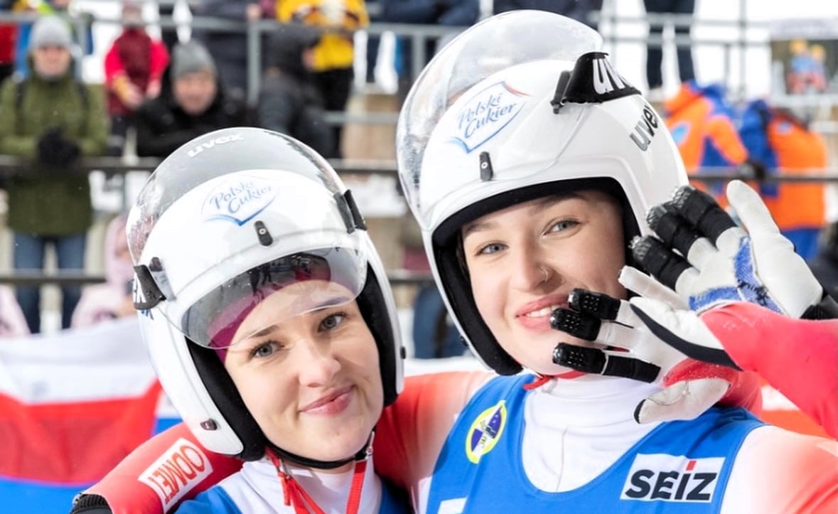 Dwie uśmiechnięte kobiety w sportowych strojach i kaskach  Saneczkarki z Nowin Wielkich jadą na igrzyska