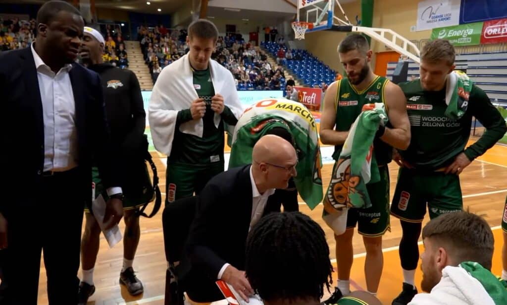 Mężczyzna w garniturze rozmawia z mężczyznami w sportowych strojach