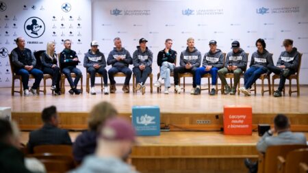 Kilkanaście osób siedzących na krzesłach na scenie  Żużel i nauka w jednej idą parze