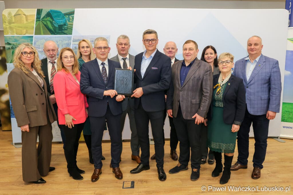 Członkowie spotkania pozują na tle ścianki promocyjnej.