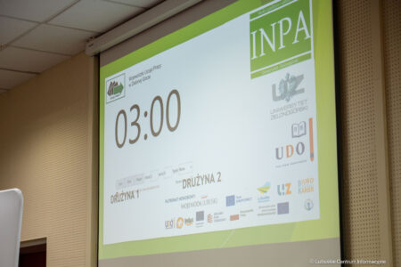 Projection screen showing a large 03:00 countdown with logos and a lime-green border in a conference room.