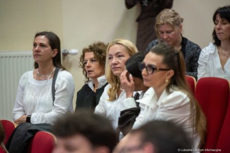 Group of women seated in a conference hall, listening attentively to a presentation.